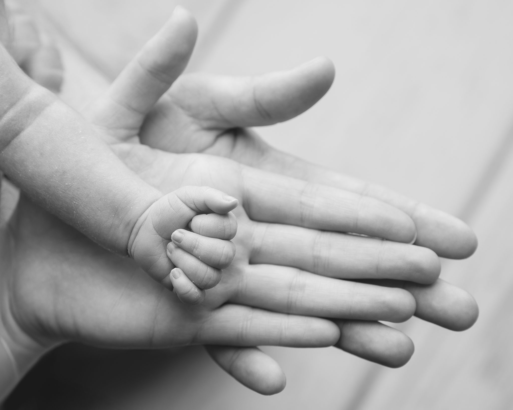 newborn baby's hand against its parents' hands, showing how tiny and perfect they are, photographed in Black and White by Newborn photographer in Somerset, Wiltshire and Bath